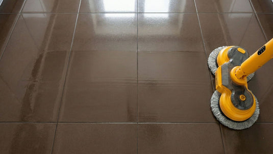 Qimedo electric spin mop scrubbing dark tile floors and grout lines with high-speed rotation.